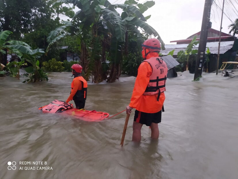 Members of the Philippine Coast Guard stand on a flooded road, after the tropical storm Megi hit, in Leyte Province