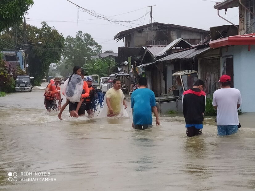 A member of the Philippine Coast Guard carries a young girl as they walk on a flooded road, after the tropical storm Megi hit, in Leyte Province
